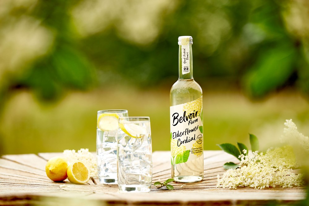 750ml Belvoir Elderflower Cordial on garden table with 2 glasses and lemons