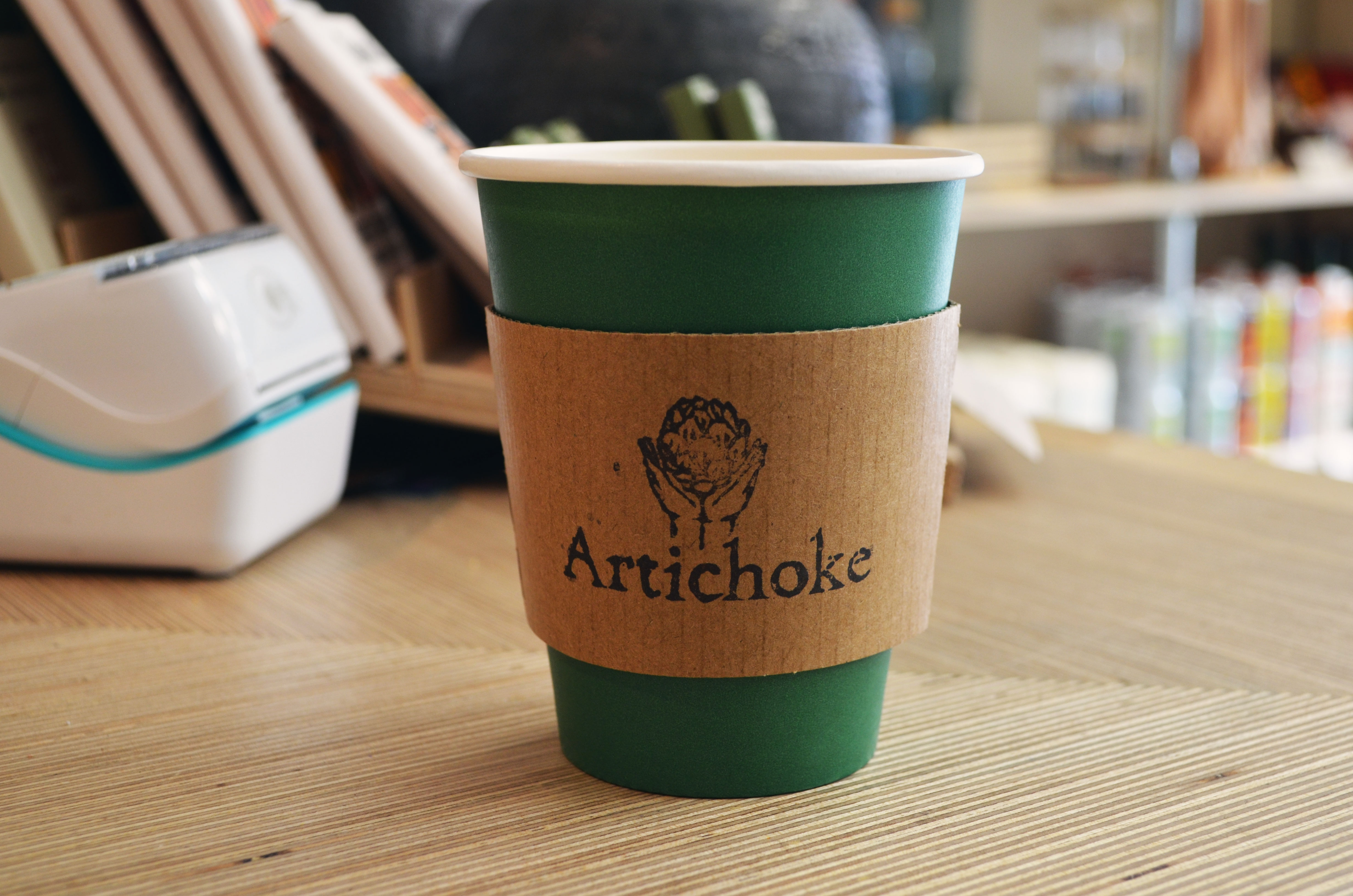 disposable coffee cup on a counter with Artichoke logo